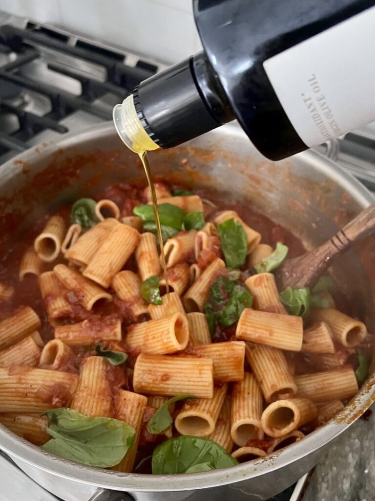 Drizzling extra virgin olive oil over pot of italian american sunday gravy.
