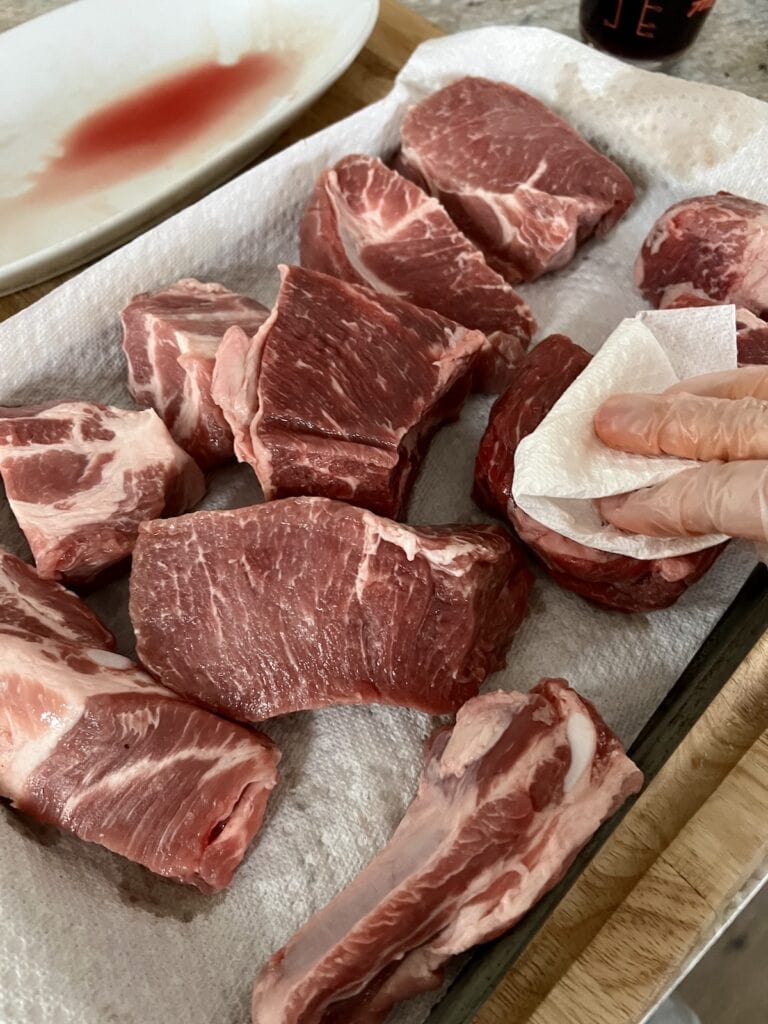Patting pieces of meat dry with paper towel for Neapolitan Ragu Recipe .