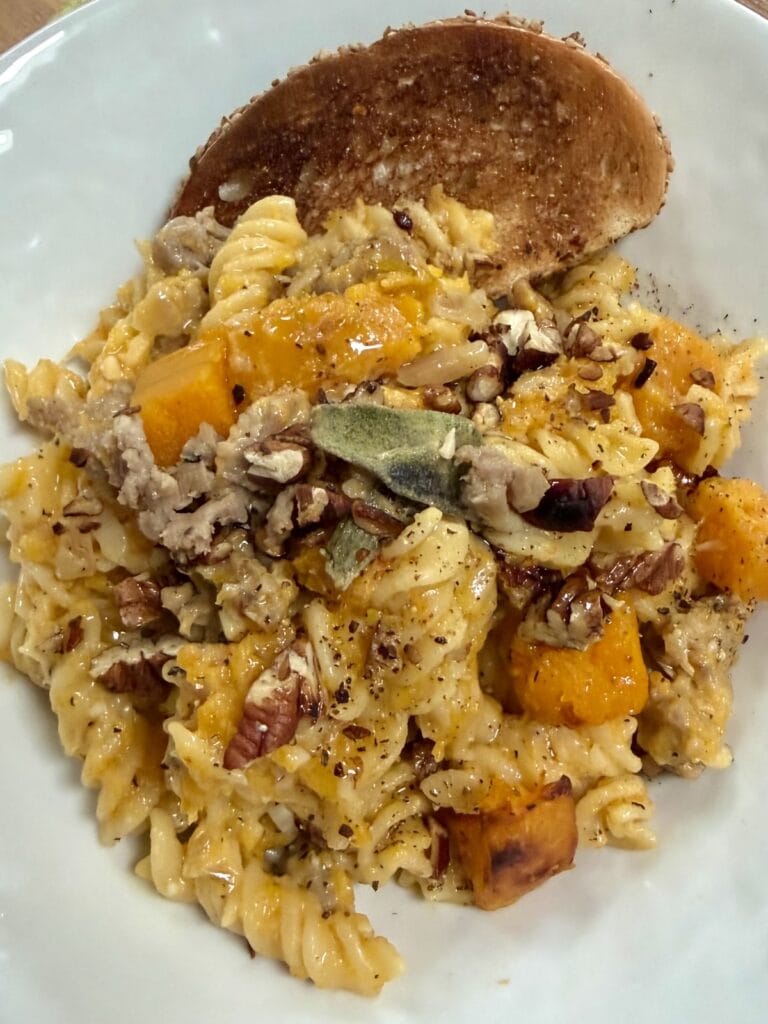 Butternut Squash and Sausage Pasta in bowl with slice of bread.