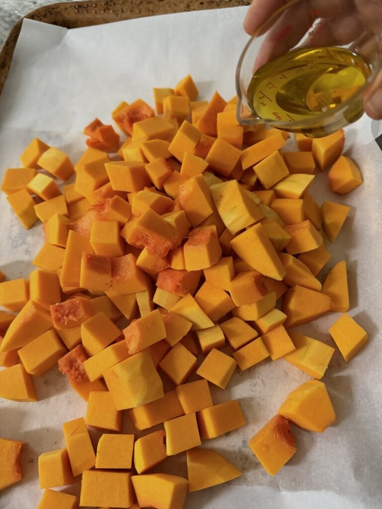 Pouring oil into diced butternut.