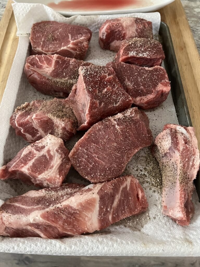 Pieces of meat seasoned with salt and black pepper ready to be browned for sunday sauce.