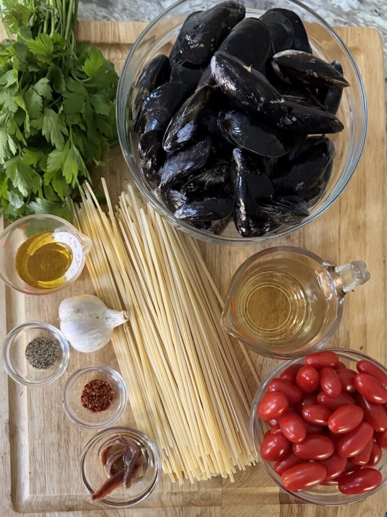All ingredients for Italian pasta with mussels on cutting board.