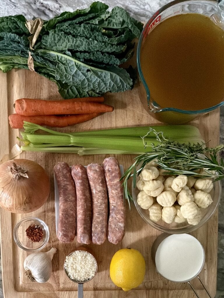 Ingredients for gnocchi and sausage soup on cutting board.