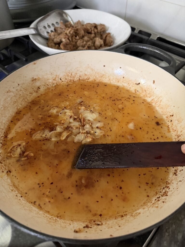 Deglazing the pan with wooden utensil and white wine.