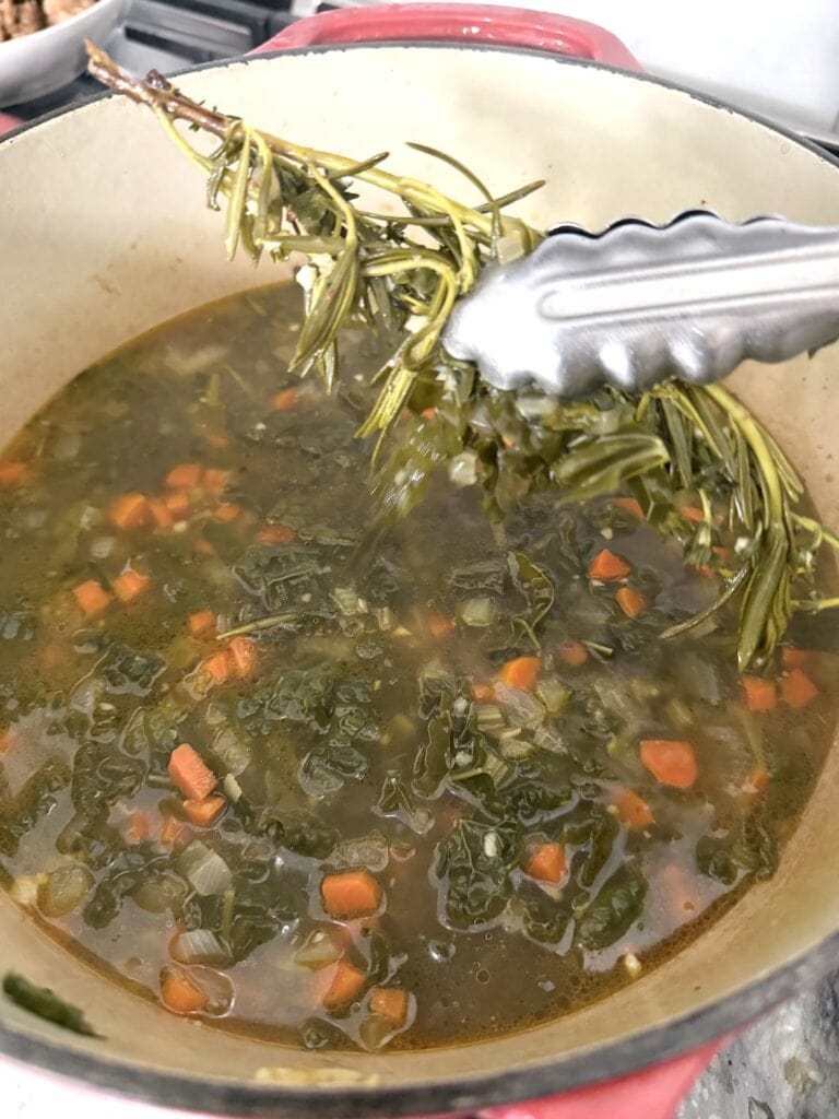 Removing the herb sprigs from the pot.
