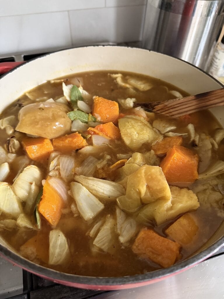 Stirring roasted vegetables in broth.