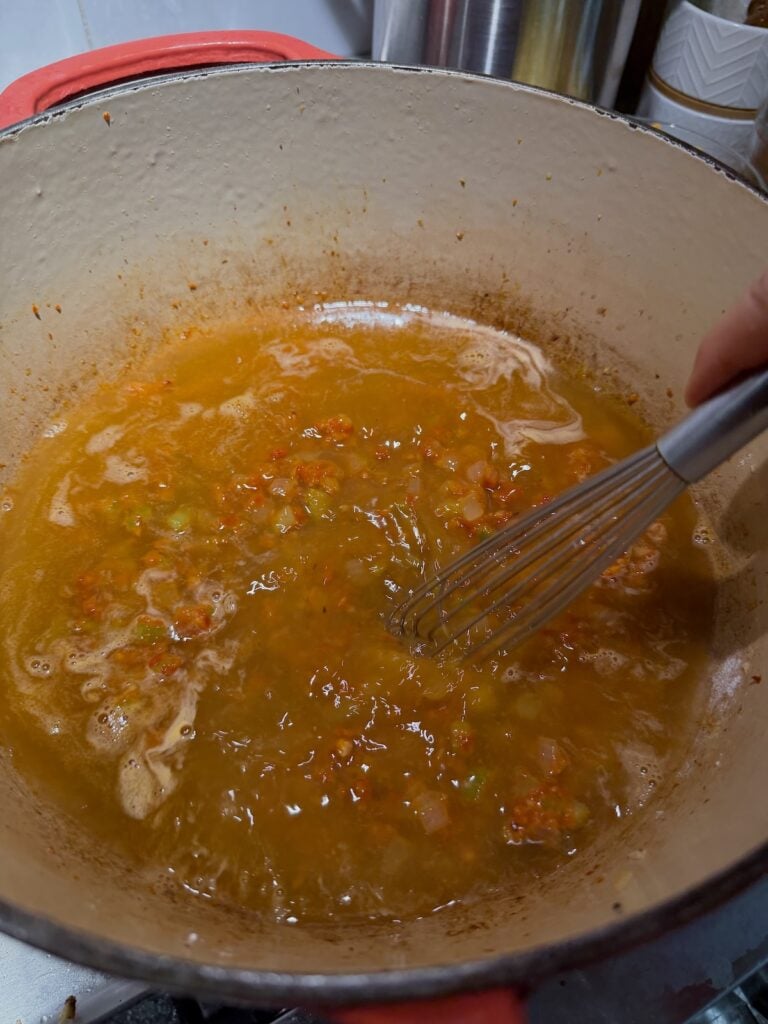 Stirring soup mixture with mix to incorporate flour and roux into the liquids.