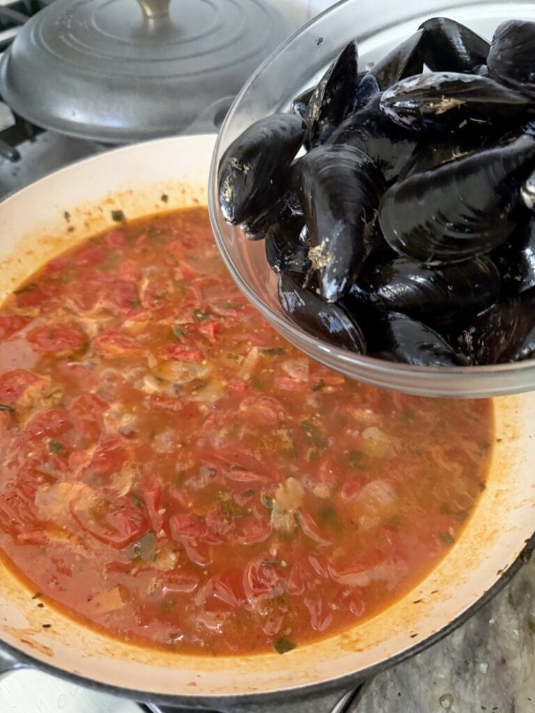 Adding mussels to tomato sauce.