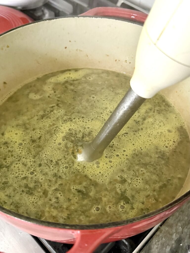 Using a immersion blender to puree the gnocchi and Italian sausage soup.