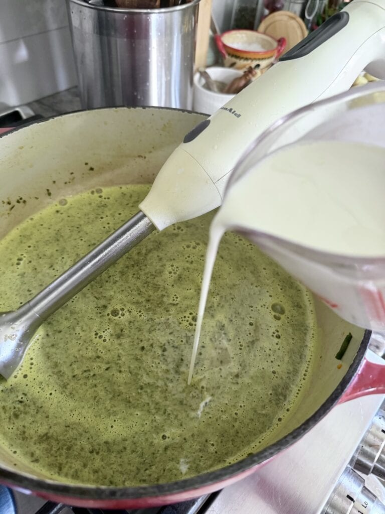 Puring heavy cream into the pureed soup.