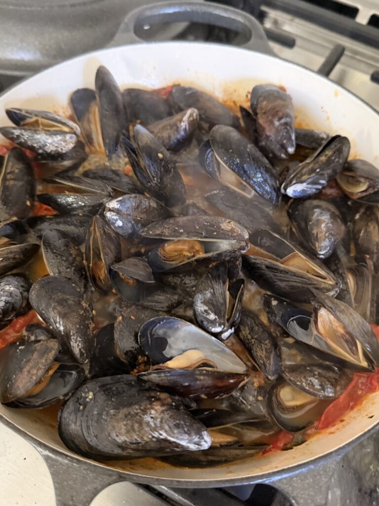 Mussels cooking in tomato sauce.