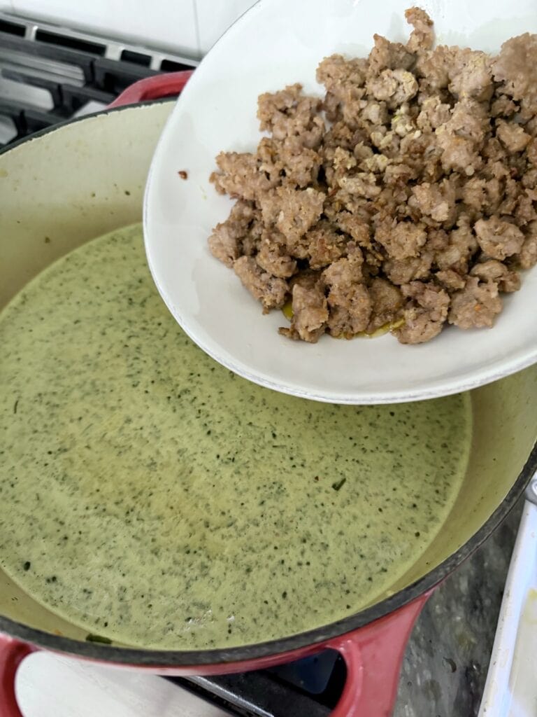 Adding the browned sausage back to the soup.