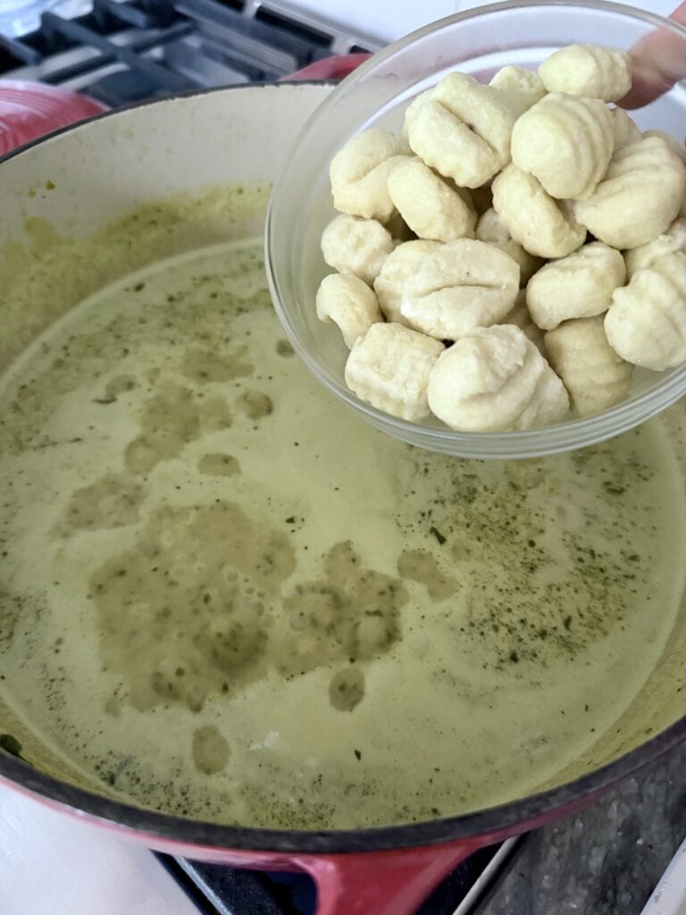 Adding the potato gnocchi to the soup. Stirring the gnocchi while it cooks in the soup.