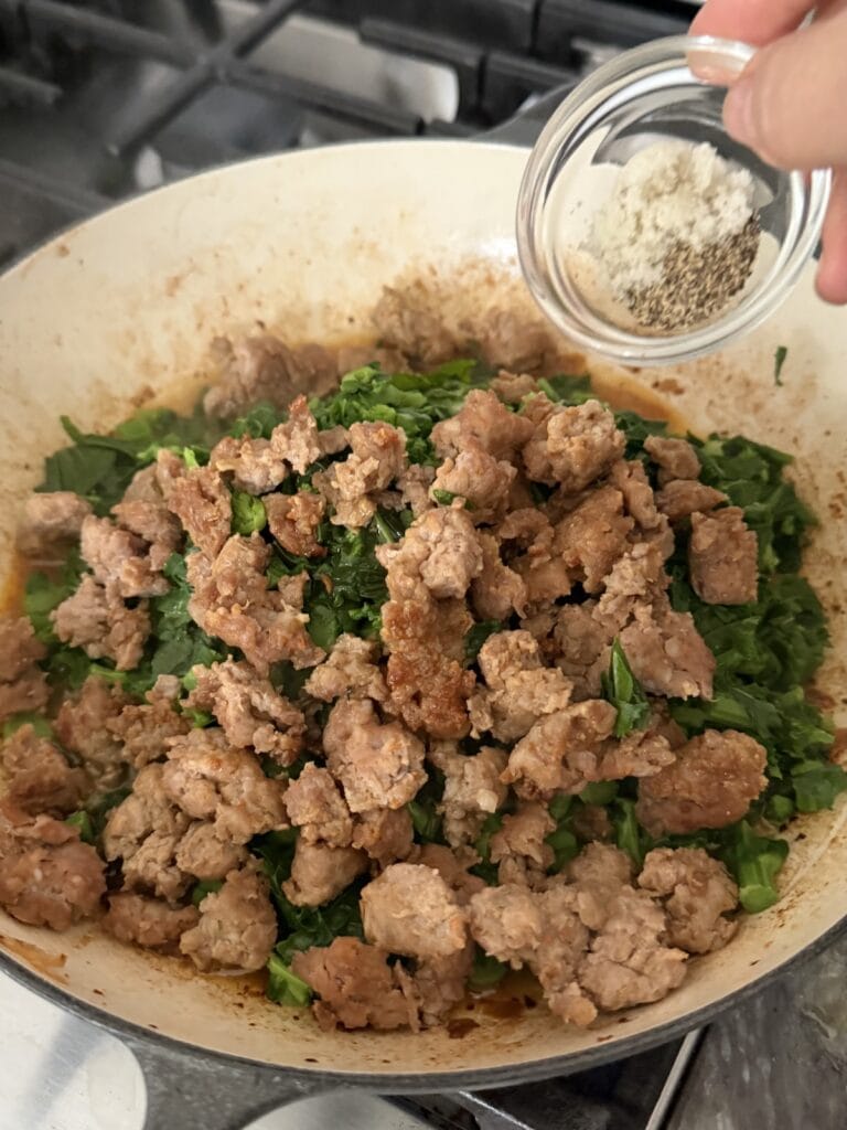 Seasoning the sausage and broccoli rabe mixture with salt and black pepper.