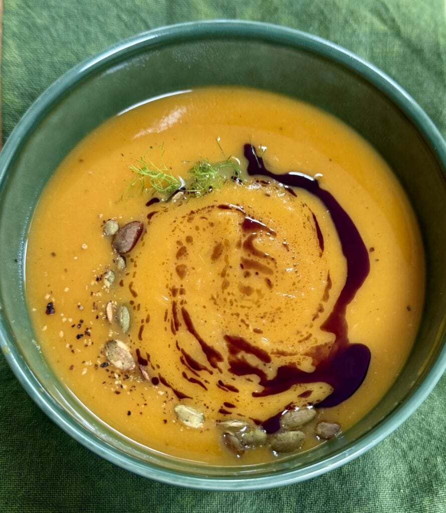 Roasted butternut squash soup in green soup bowl over green towel.