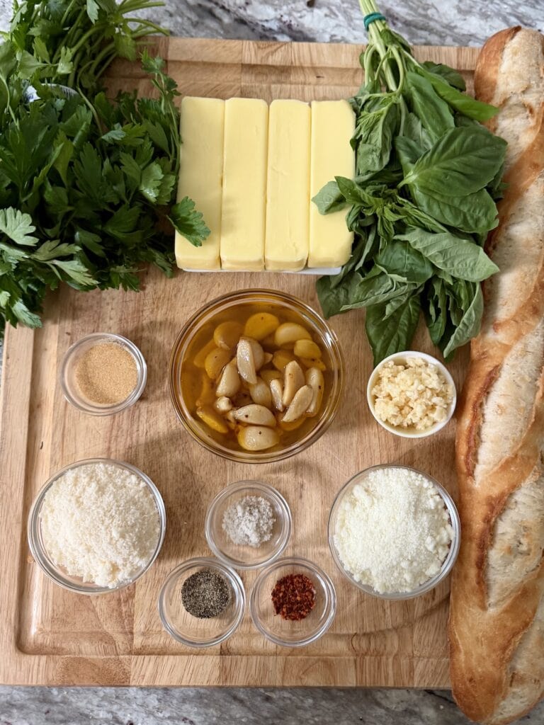 All ingredients for homemade cheesy garlic bread baguette on cutting board.