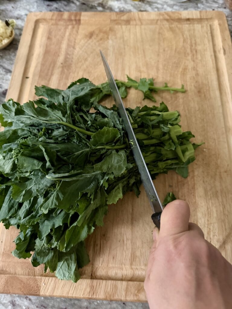 Slicing rapini stems with knife.