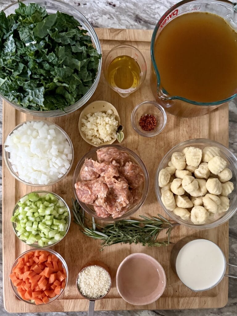 Prepped ingredients for gnocchi and sausage soup on cutting board.