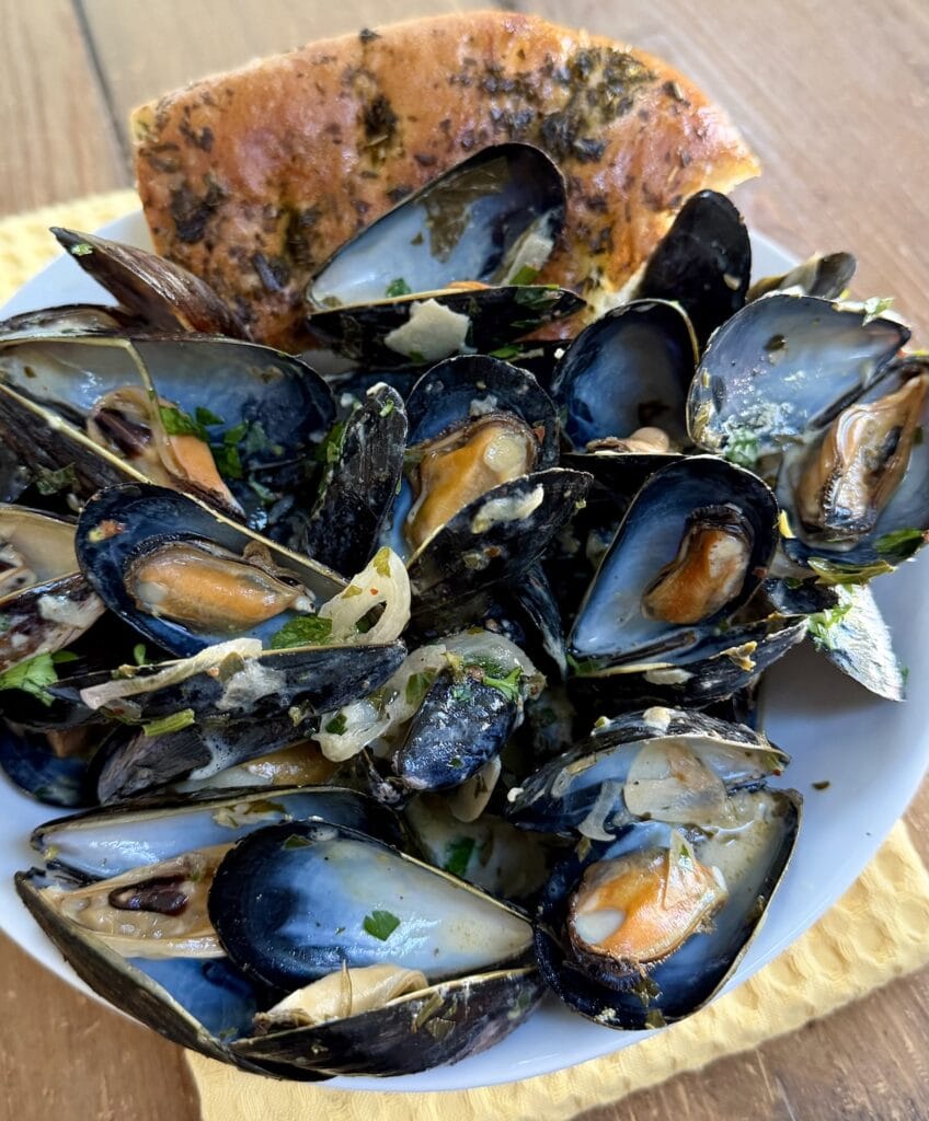 White wine mussels with focaccia in serving bowl.