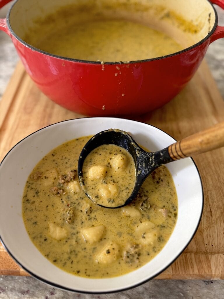 Ladling Italian Sausage Gnocchi Soup from Dutch oven to soup bowl.