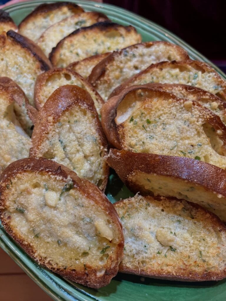 Broiled garlic bread sliced on green platter.