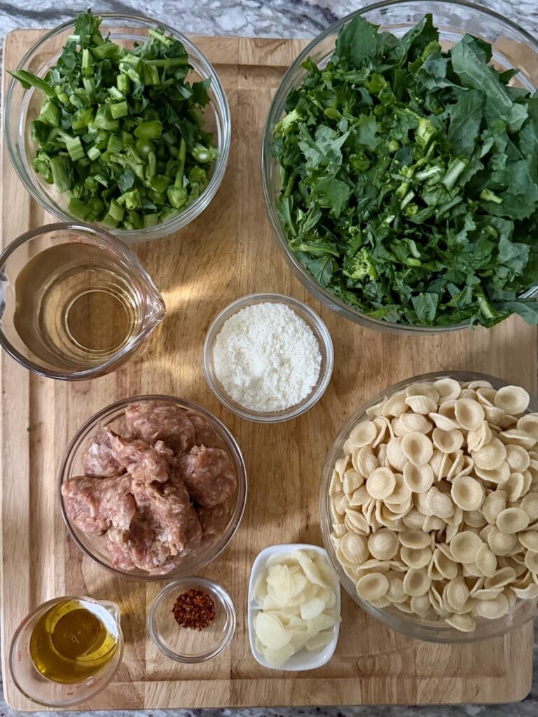 Prepped ingredients for Orecchiette With Broccoli Rabe and Sausage on cutting board.