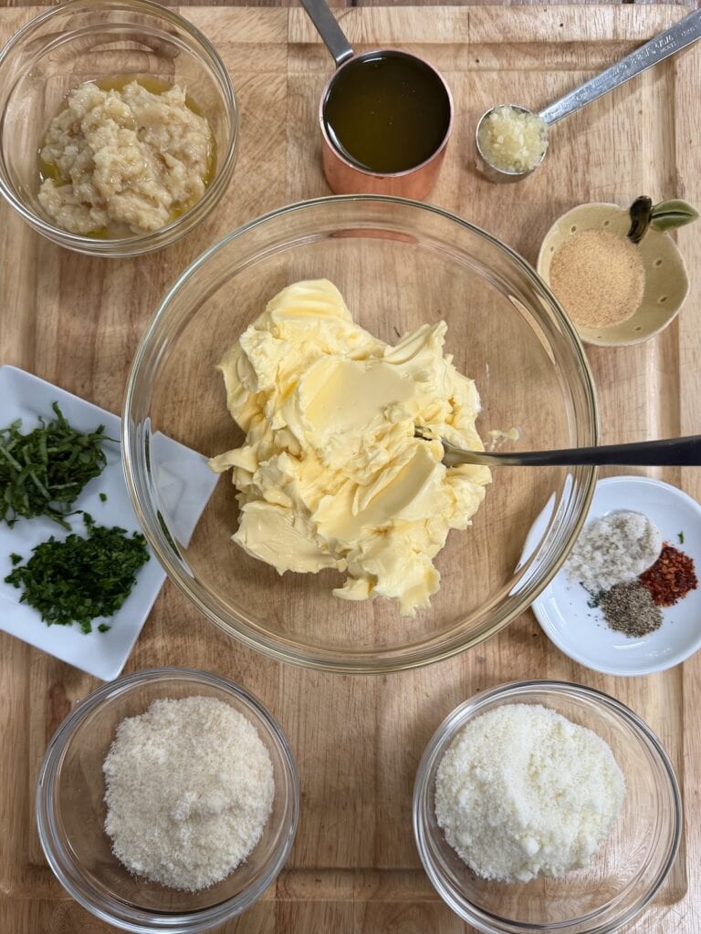 All prepped ingredients for garlic butter for garlic bread on cutting board.