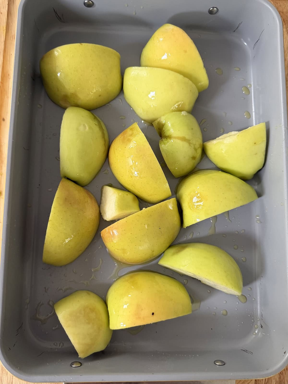 Quartered apple pieces in baking dish ready to be roasted.