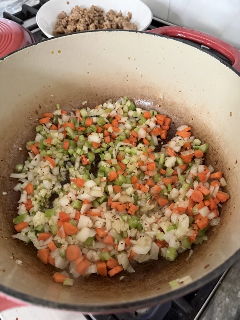 Sautéing carrots, onions, celery and garlic in Dutch oven for Italian sausage and gnocchi soup.