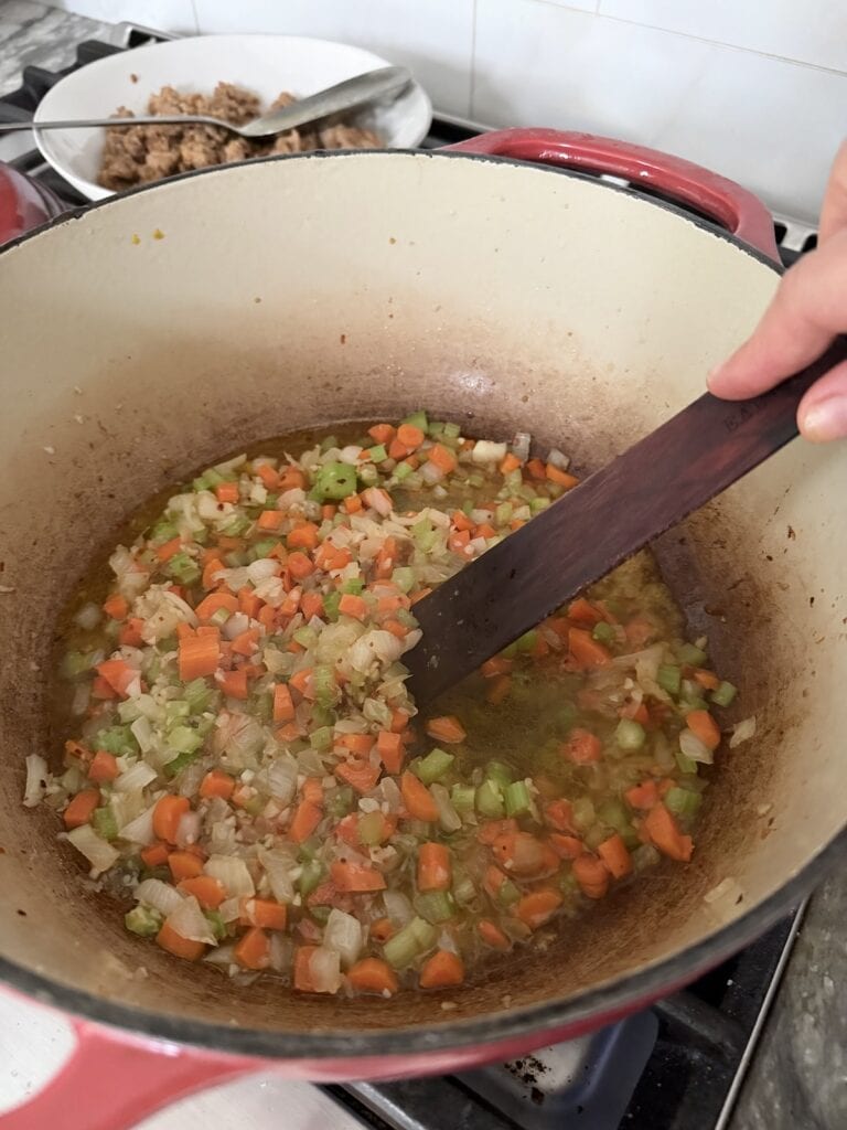 Deglazing the pan with white wine and a wooden utensil.