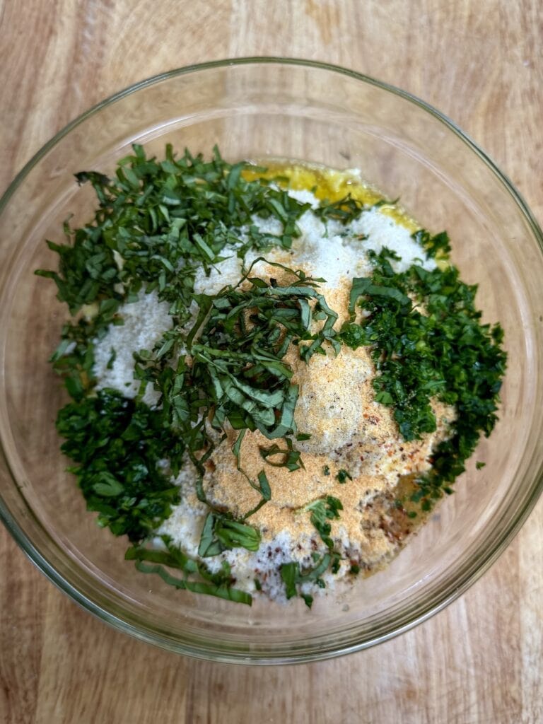 All ingredients for garlic butter in bowl, ready to be mixed.