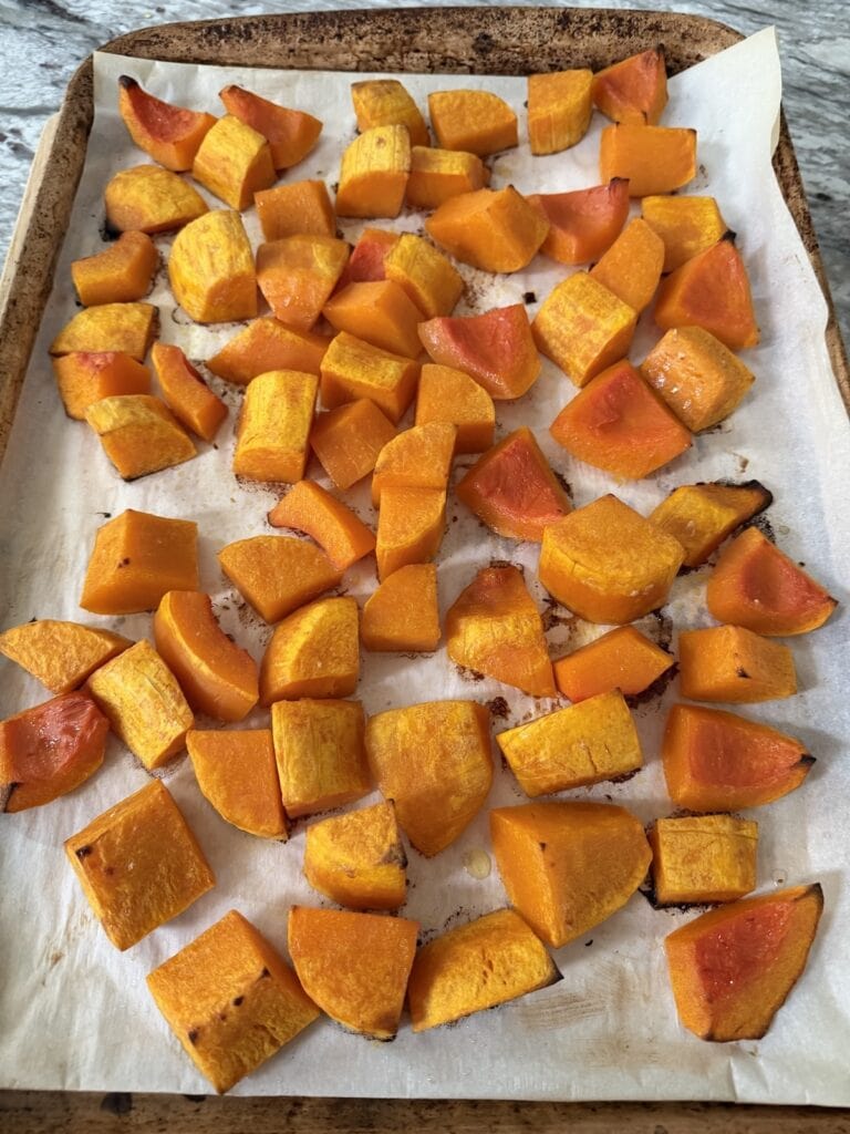 Butternut squash on parchment-lined sheet pan after being roasted.
