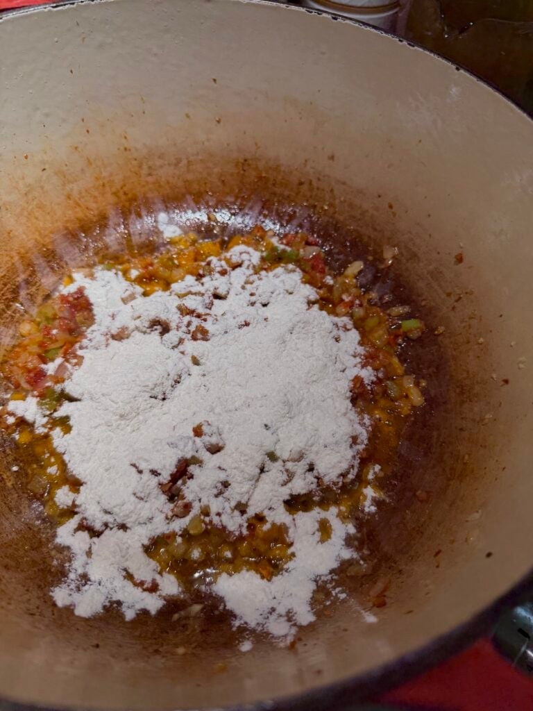 Flour added to sautéed veggies in pot.