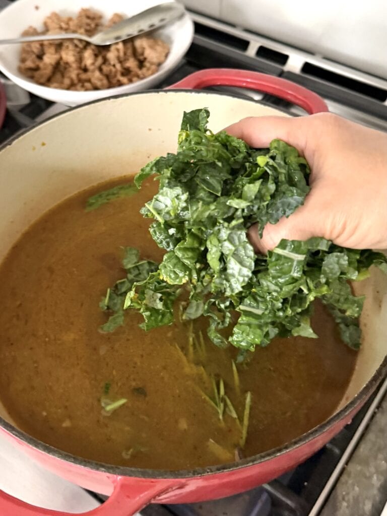 Adding chopped kale to the broth.